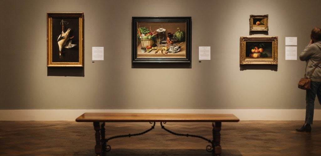 Interior of the San Diego Museum of Art featuring Renaissance paintings and a bench with dim lighting in Balboa Park, San Diego
