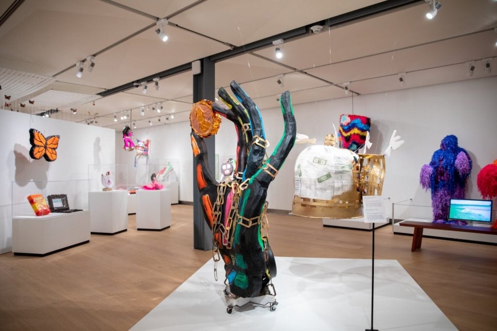 Interior of the Mingei International Museum featuring a large, colorful sculpture of a hand holding a coin