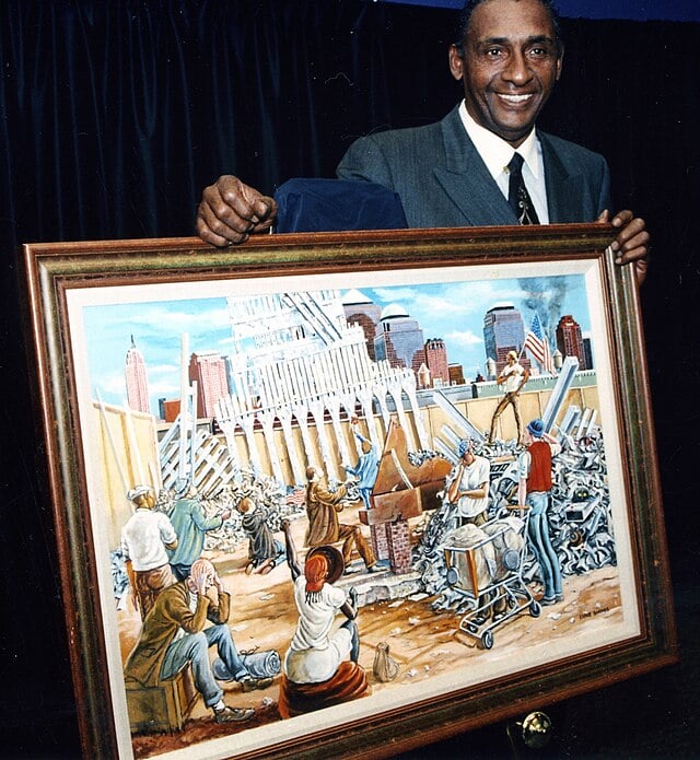 NFL player and painter Ernie Barnes standing with his painting