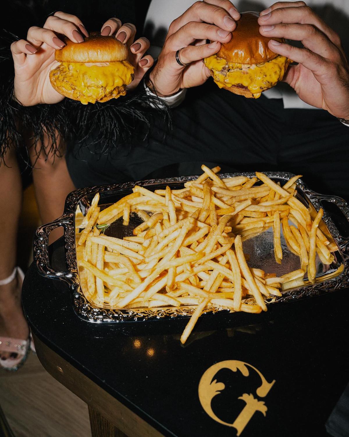 Two people eating burgers in fancy attire at San Diego bar and restaurant the Gaslamplighter